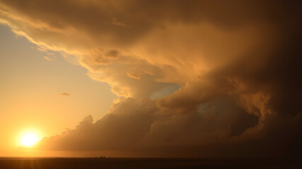 Fototapeta premium Sun setting behind a line of thunderstorms on the horizon, dramatic weather, contrast of light and dark