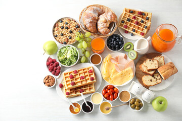Different meals served for breakfast on white table, flat lay