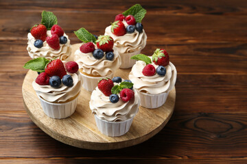 Tasty cupcakes with different berries and mint on wooden table