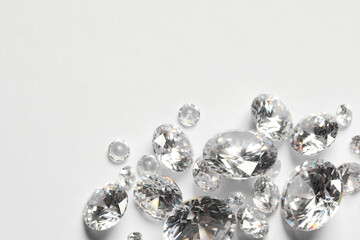 Many beautiful shiny diamonds on white background, flat lay. Space for text