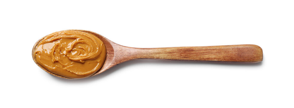 Tasty peanut butter in spoon isolated on white, top view