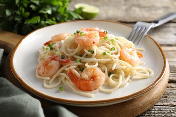 Delicious pasta with shrimps and green onions on wooden table, closeup