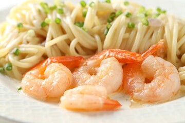 Delicious pasta with shrimps and green onions on plate, closeup