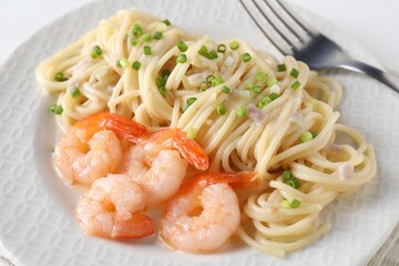 Delicious pasta with shrimps and green onions on plate, closeup