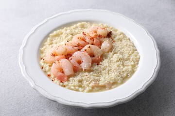 Delicious risotto with shrimps and cheese on light grey table, closeup