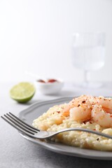Delicious risotto with shrimps and cheese on light grey table, closeup