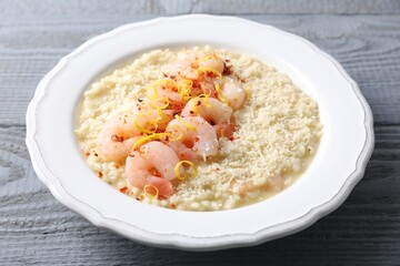Delicious risotto with shrimps and cheese on grey wooden table, closeup