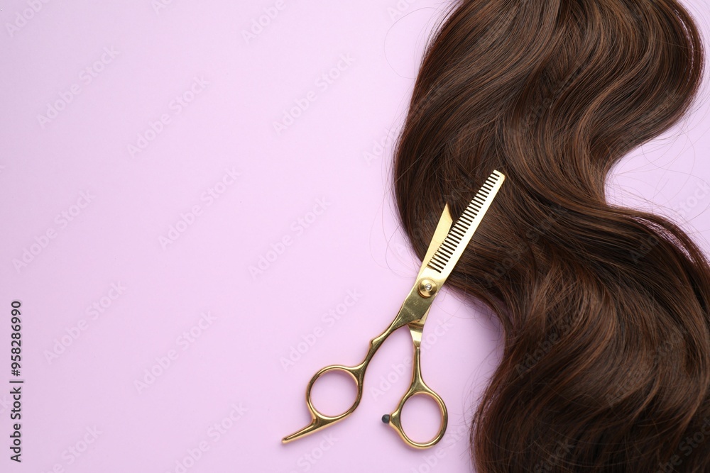 Wall mural brown hair strand and professional scissors on violet background, top view. space for text