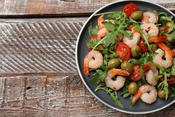 Delicious shrimp salad with tomato and olives on wooden table, top view. Space for text
