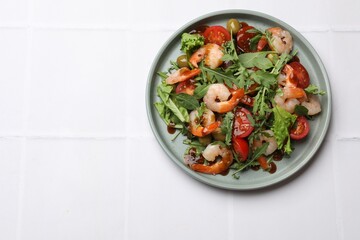 Delicious shrimp salad with vegetables on white tiled table, top view. Space for text