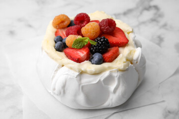 Pavlova cake (meringue dessert) with whipped cream, fresh berries and mint on white marble table, closeup