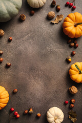 Autumn frame of colorful pumpkins, nuts, and foliage on a rustic background. Perfect for seasonal designs