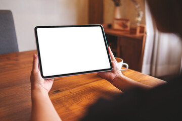 Mockup image of a woman holding digital tablet with blank desktop screen at home