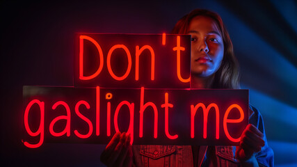 Don't gaslight me neon sign held by Young woman in a dark room. Concept manipulation in abusive relationships with a narcissist partner or toxic co-worker