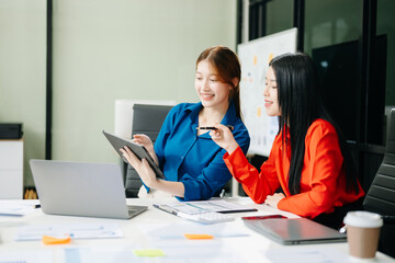 Asian business colleague business presents and explains and using laptop and tablet. Teamwork, financial