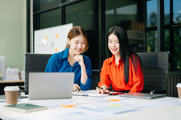 Asian business colleague business presents and explains and using laptop and tablet. Teamwork, financial