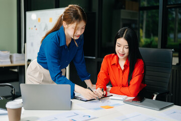 Asian business colleague business presents and explains and using laptop and tablet. Teamwork, financial