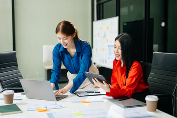 Asian business colleague business presents and explains and using laptop and tablet. Teamwork,...