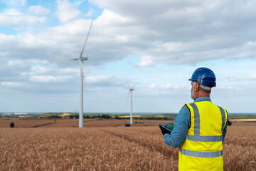 A Wind Energy Technician Analyzes Data in a Vast Wheat Field Under a Cloudy Sky in Autumn