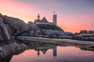 Saint-Mathieu Lighthouse at sunrise, with cliff rocks on foreground, on Pointe Saint-Mathieu in Plougonvelin, Brest, France