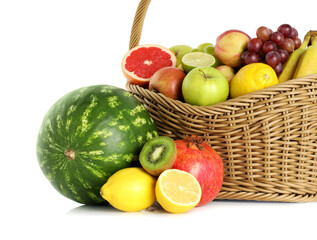Many different fresh fruits in wicker basket isolated on white