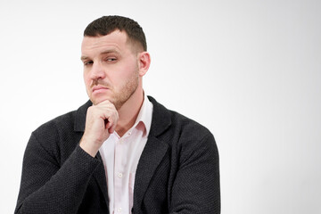 Handsome young pensive man standing against gray background with copy space