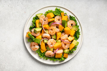 Salad with mango, shrimp and avocado on white plate, top view. 