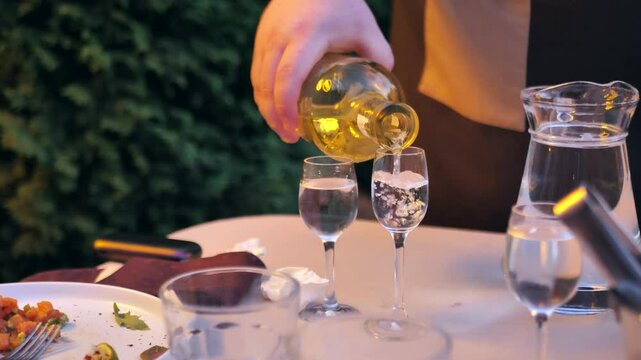 waiter pouring gin from bottle into glass in restaurant. dutch gin. spirit