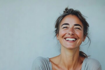 Happy woman laughing against plain background