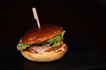 Chiken cheese burger with bacon on black background