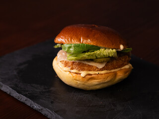 Chiken cheese burger with bacon on black background