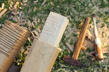 unfinished wooden pergola columns with hammer and chisel on grass. carpentry work in the garden