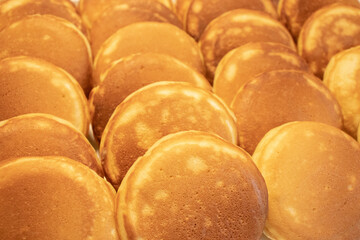 Close-up of neatly arranged golden brown fluffy pancakes on a tray.