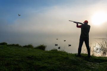 Waterfowl Hunter Aiming At Duck At Sunrise.