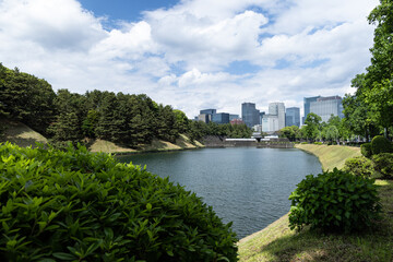 青空と雲と緑に包まれた皇居のお堀と東京のオフィスビル群