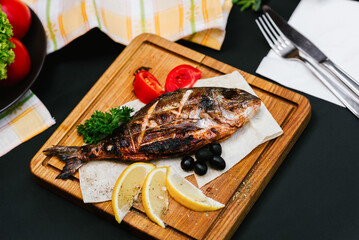 fire-baked fish on a plate with vegetables, a bright dish