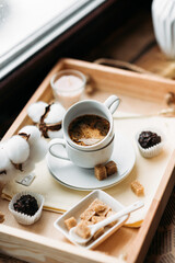 morning coffee in a white cup, espresso, americano, breakfast on a wooden tray on the windowsill, brown sugar, candy, coffee in bed, cotton flowers, candles, romance