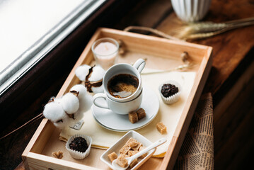 morning coffee in a white cup, espresso, americano, breakfast on a wooden tray on the windowsill, brown sugar, candy, coffee in bed, cotton flowers, candles, romance
