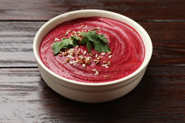 Tasty beetroot hummus, parsley and seeds in bowl on wooden table, closeup