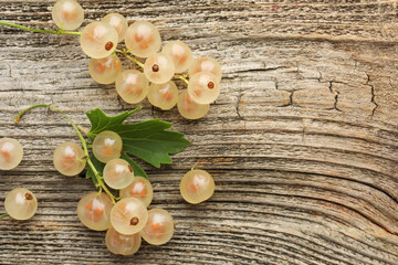 Fresh white currant berries and green leaf on wooden table, top view. Space for text