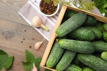 Fresh green cucumbers and spices on wooden table, flat lay
