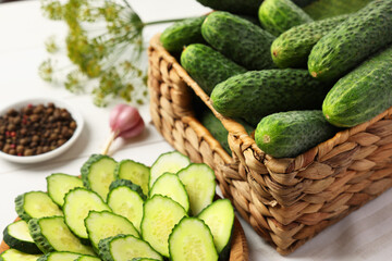 Fresh whole and cut cucumbers on white table, closeup
