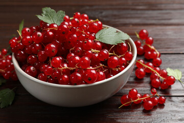 Fresh red currants in bowl on wooden table, closeup