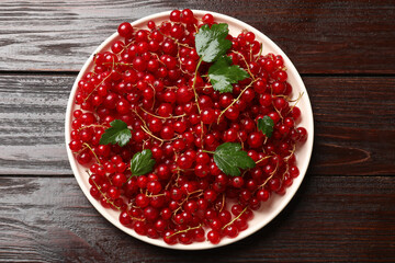 Fresh red currants and green leaves on wooden table, top view