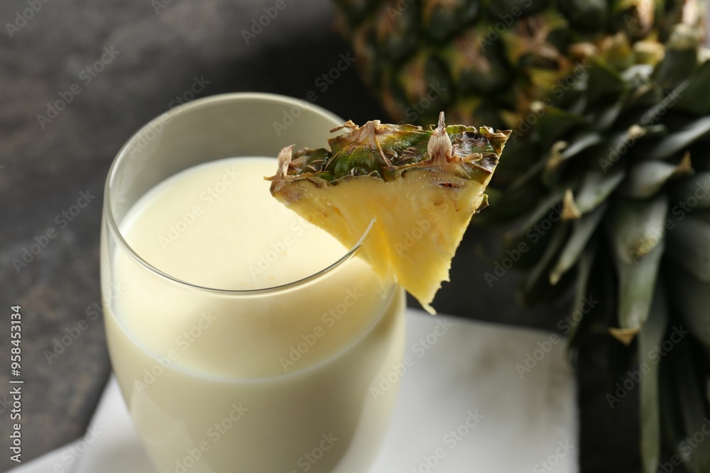 Sticker Tasty pineapple smoothie in glass and fresh fruit on table, closeup