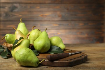 Fresh green pears, leaves and knife on wooden table, closeup. Space for text