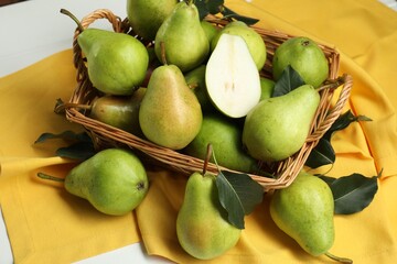 Fresh green pears with leaves and basket on white table, above view