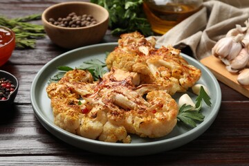 Delicious baked cauliflower steaks with garlic and parsley on wooden table, closeup