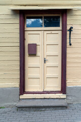 Obraz premium A charming yellow wooden door with a mailbox in a quaint neighborhood during the day