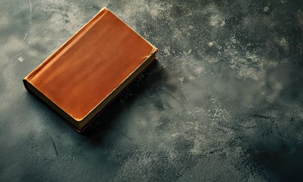A closed orange book on a textured dark background